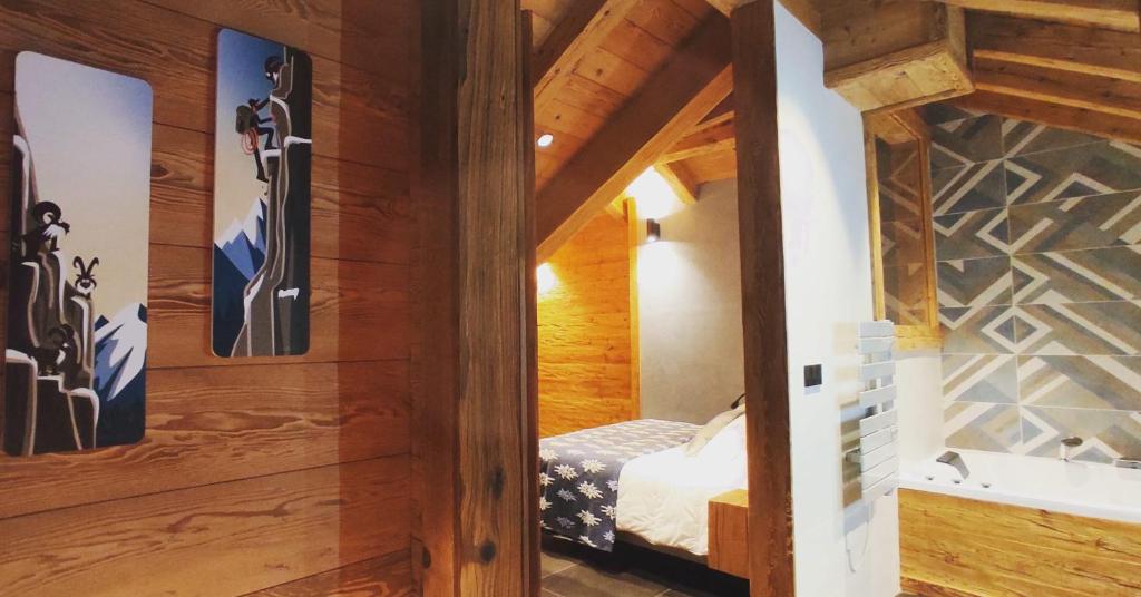 ein Schlafzimmer mit einem Bett in einem Zimmer mit Holzwänden in der Unterkunft Esprit de la Meije - Chalet overlooking the Meije in La Grave