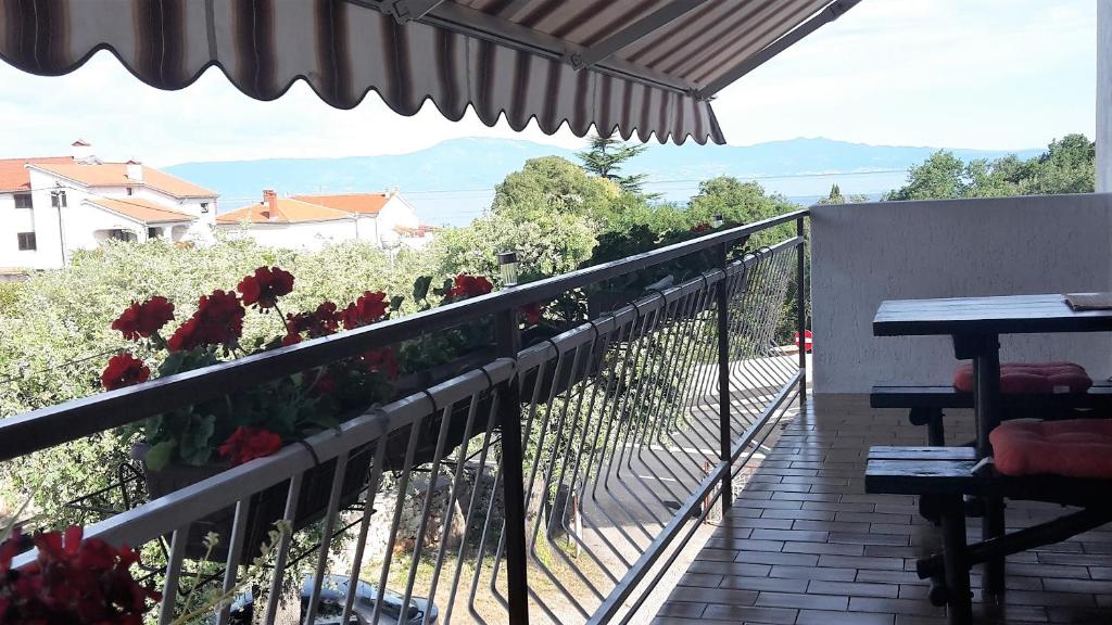 - un balcon avec des fleurs rouges sur une balustrade dans l'établissement Apartments Sabina i Grapes, à Malinska