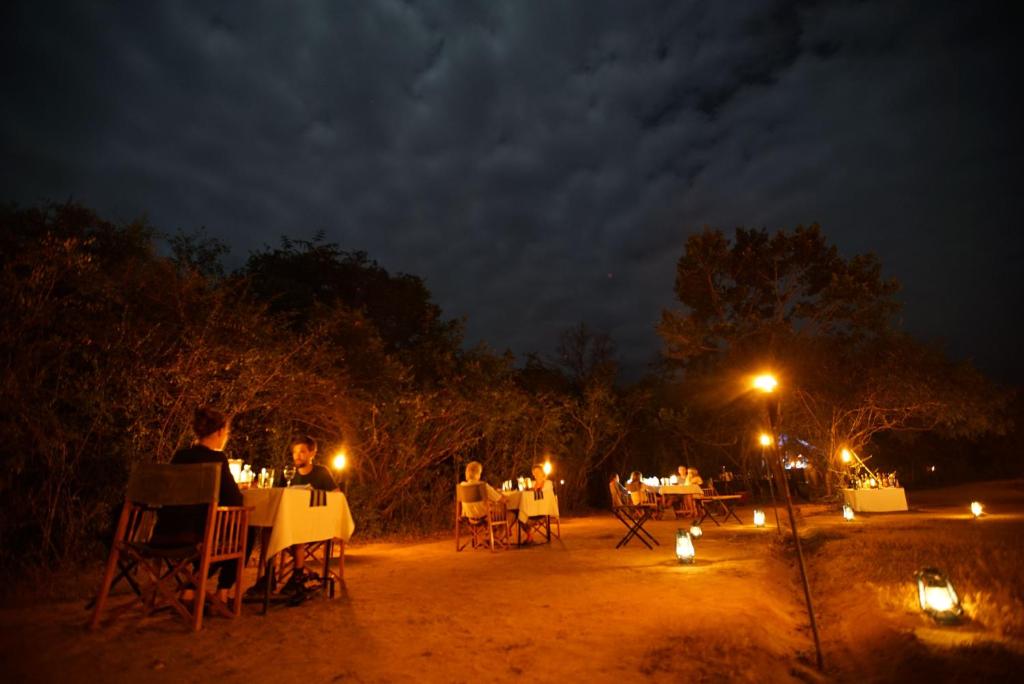 a group of people sitting at tables at night at Mahoora Wilpattu - by Eco Team in Wilpattu