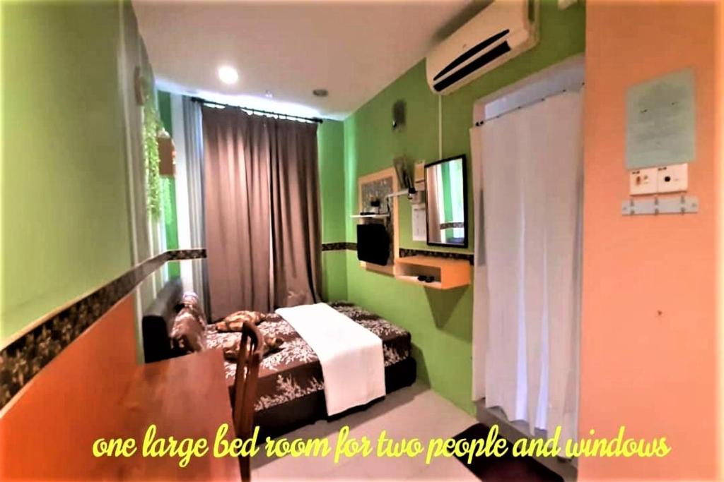 Hotel Sri Bahau في Bahau: غرفة خضراء فيها سرير وتلفزيون