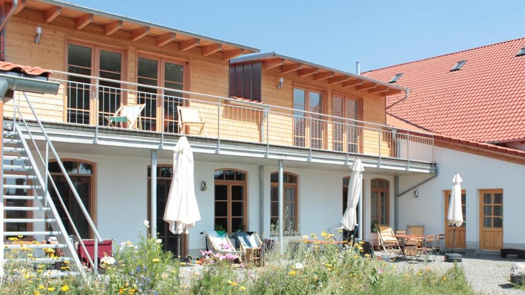 a house with a balcony with chairs and umbrellas at Allgäu Ferienhof Schönberger in Argenbühl