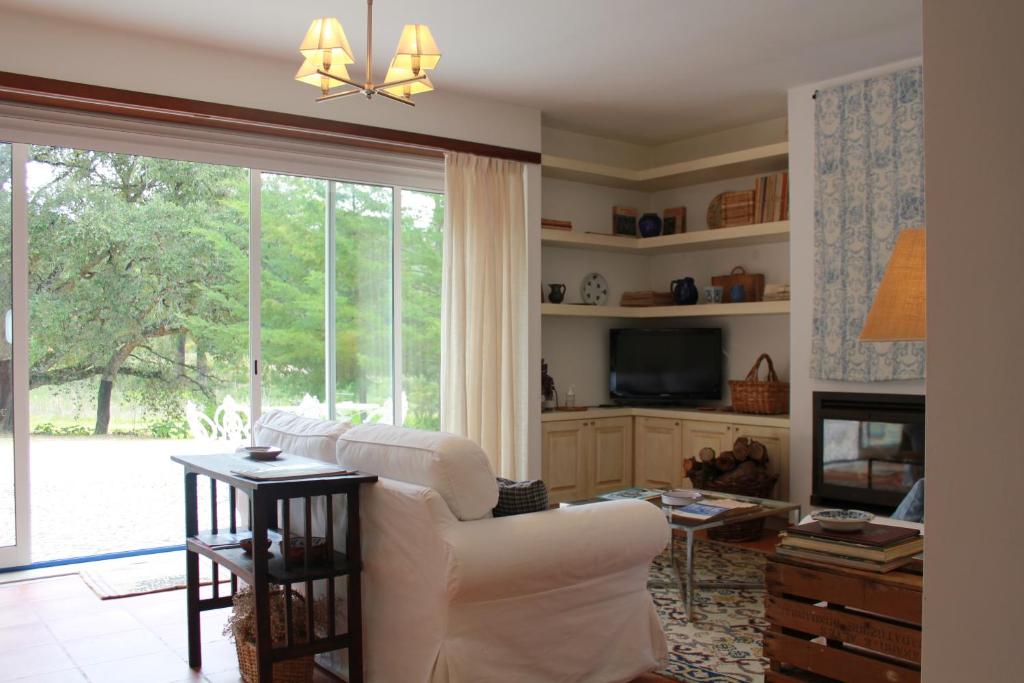 uma sala de estar com um sofá branco e uma grande janela em Quinta Dos Anjos em Santarém