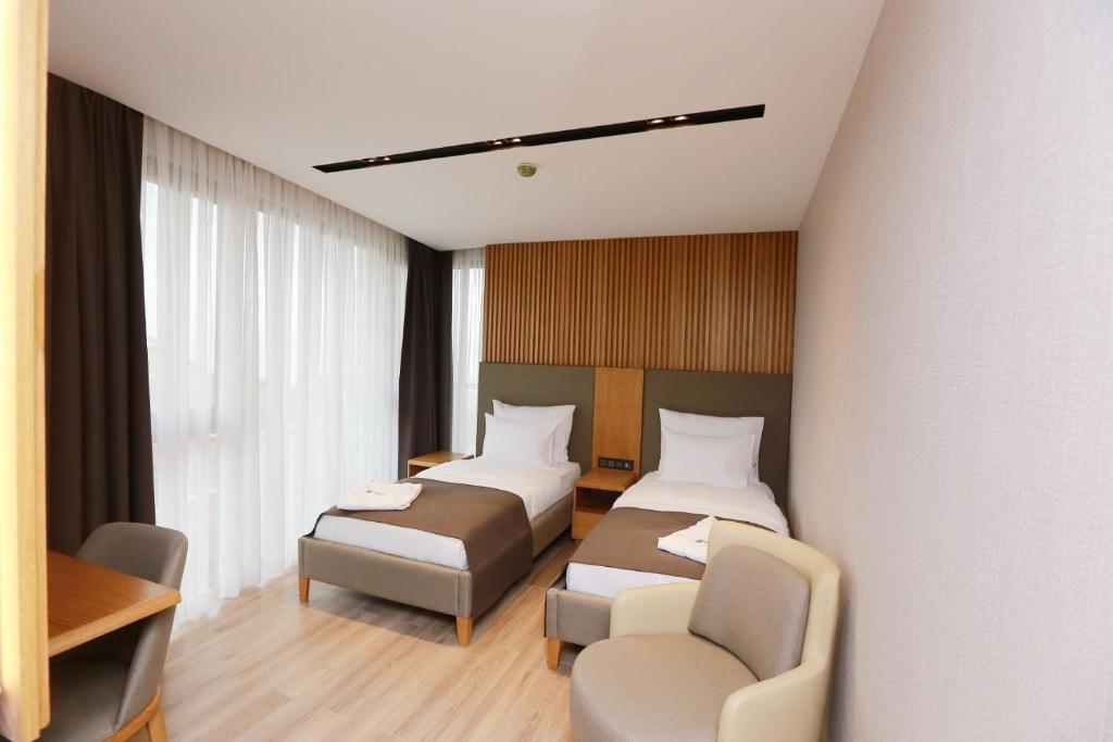 una habitación de hotel con 2 camas y una silla en Pikola Otel, en Ordu