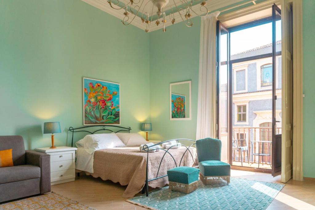 a bedroom with a bed and a chair and a window at Sicily in Home Centro Catania Pescheria in Catania