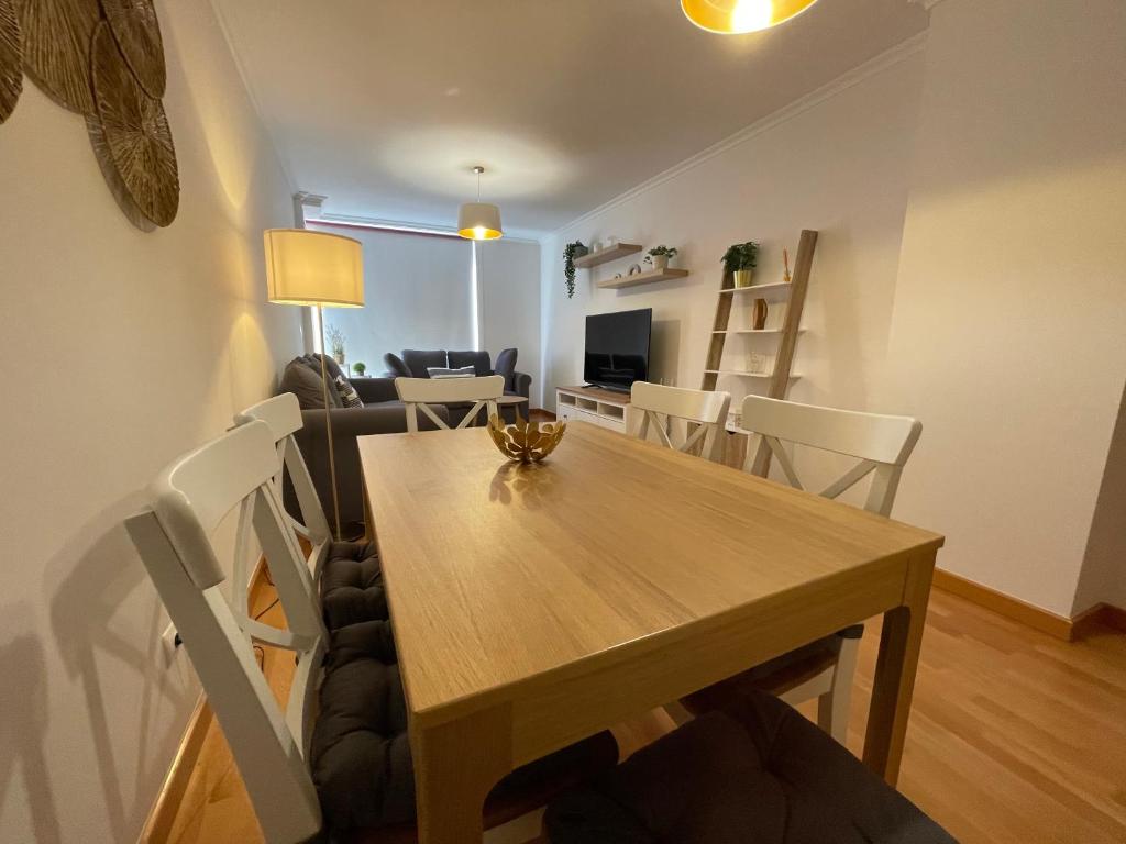 a dining room and living room with a wooden table and chairs at OKTHEWAY Castelao Street in Sarria