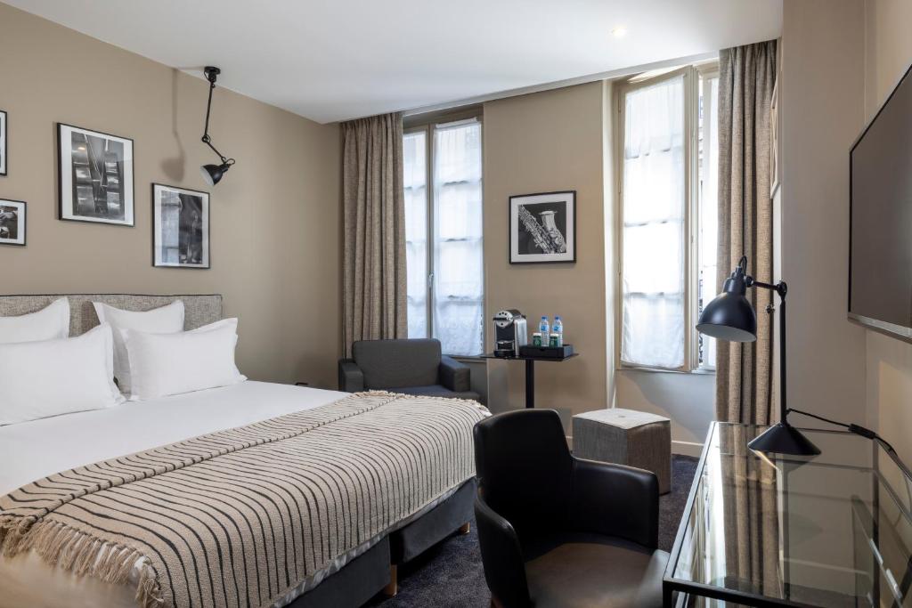 a hotel room with a bed, desk, mirror and window at Hôtel Hélios Opéra in Paris