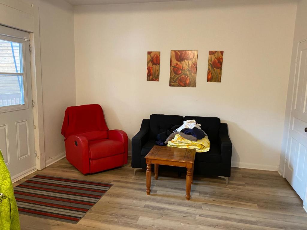 a living room with a black couch and a red chair at Gestion clin d Oeil 349 in La Tuque