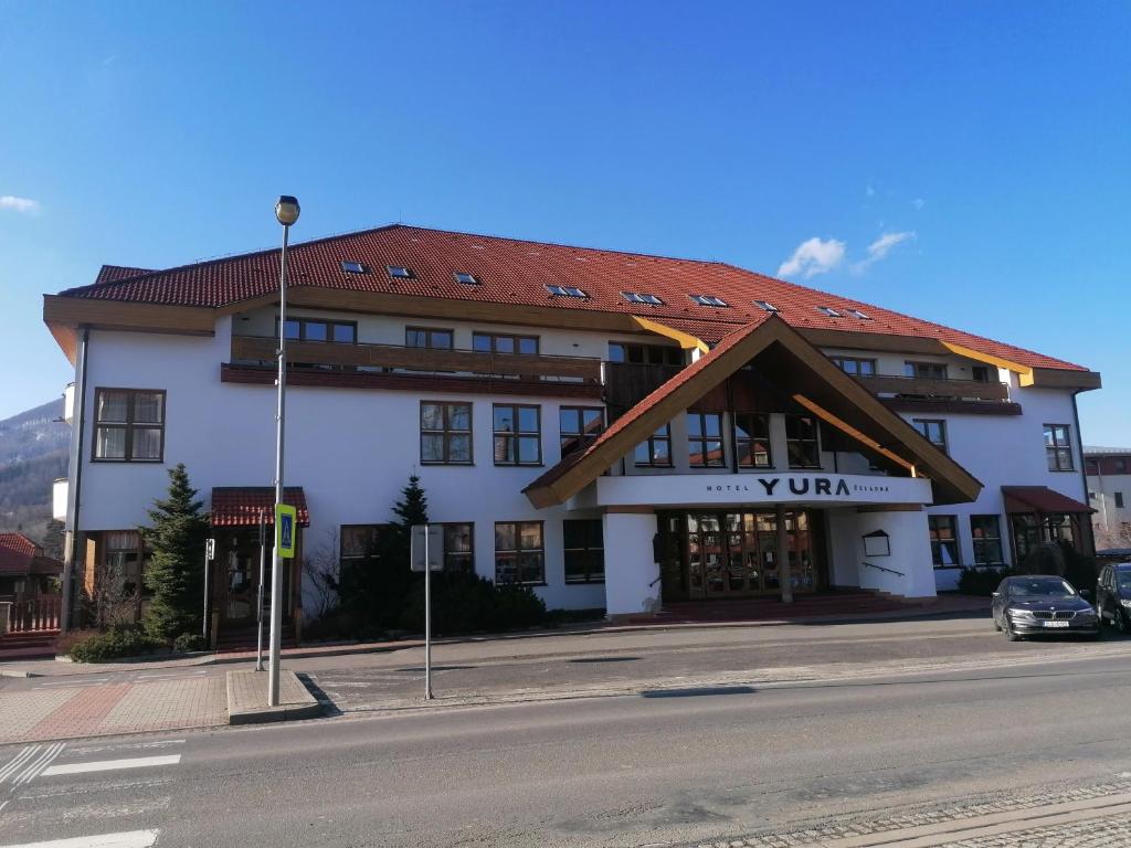切拉德納的住宿－YURA hotel Čeladná -BAZÉN A SAUNA ZDARMA，一座白色的大建筑,有红色的屋顶