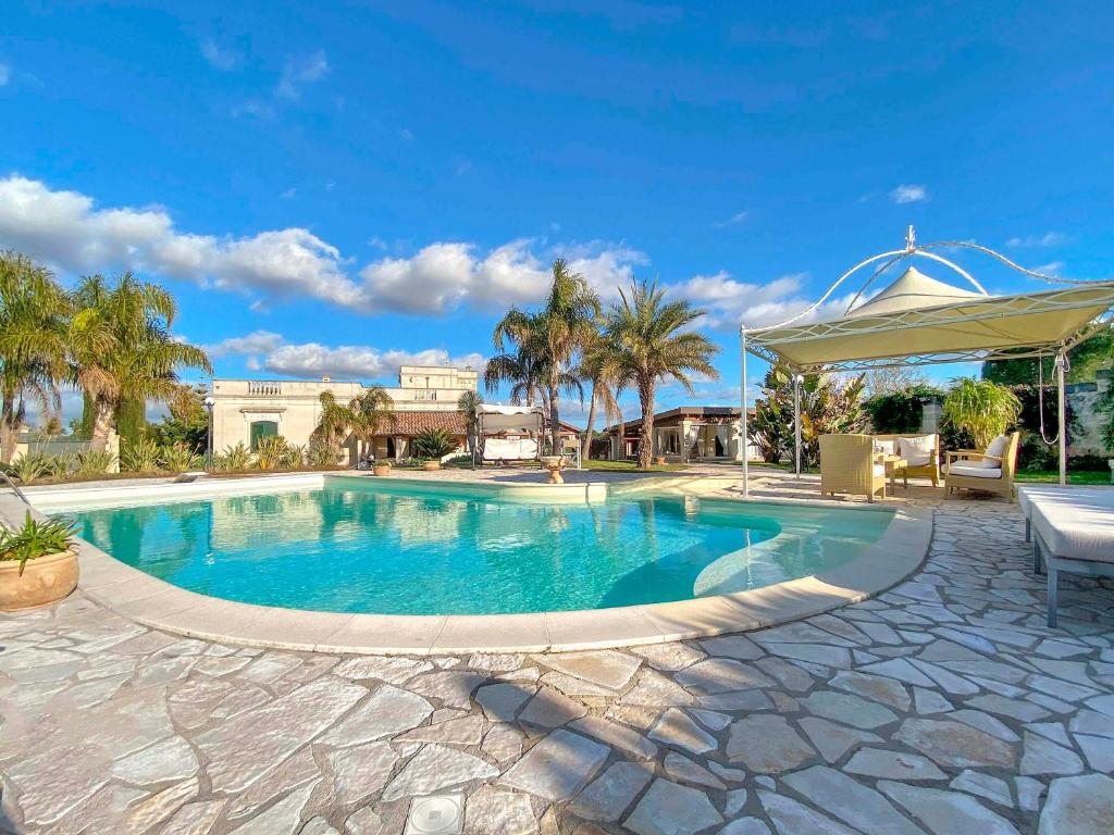 duży basen z parasolem i palmami w obiekcie Villa Nicrys by Perle di Puglia w mieście Maglie