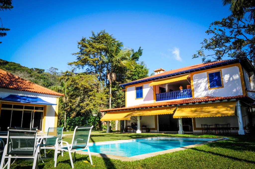 a villa with a swimming pool in front of a house at Pousada Vila Brasil in Petrópolis