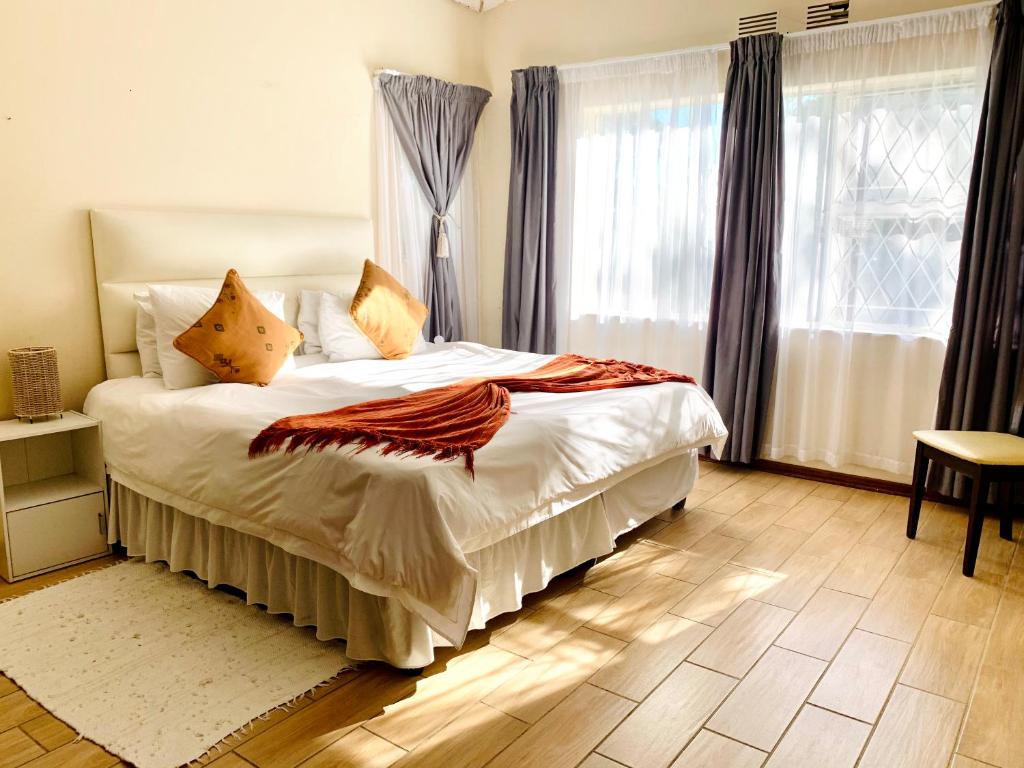 1 dormitorio con 1 cama con sábanas y almohadas blancas en 77 on Sissons, en Mthatha