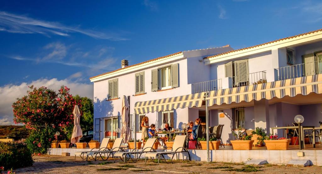 un gruppo di persone seduti fuori da un edificio di Villa Pischinas a Magomadas