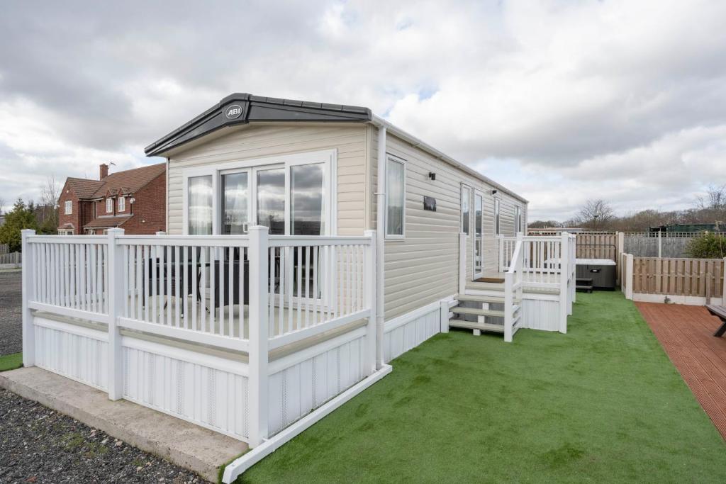 a white tiny house on a green lawn at Hallcroft Fishery And Holiday Park in Retford