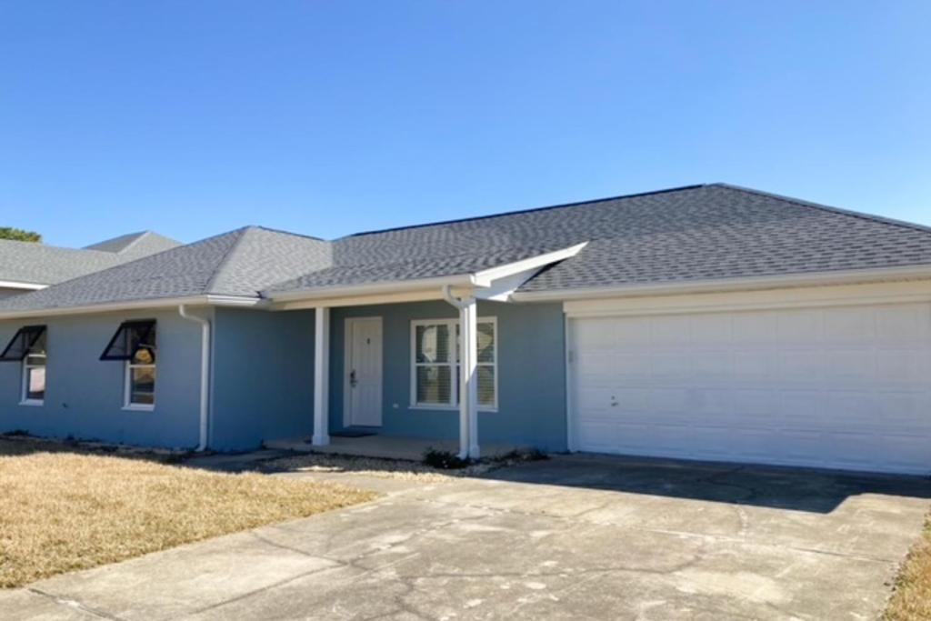 a blue house with a white garage at Lagoon Retreat in Pensacola