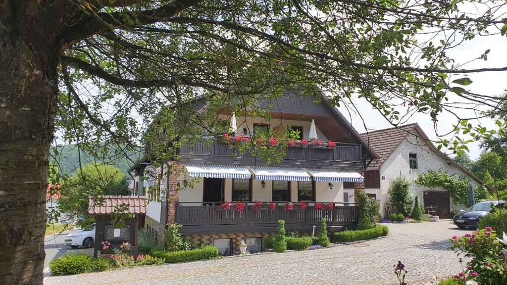 a house with a balcony with red flowers on it at Hotel Pension Wolf in Ebermannstadt