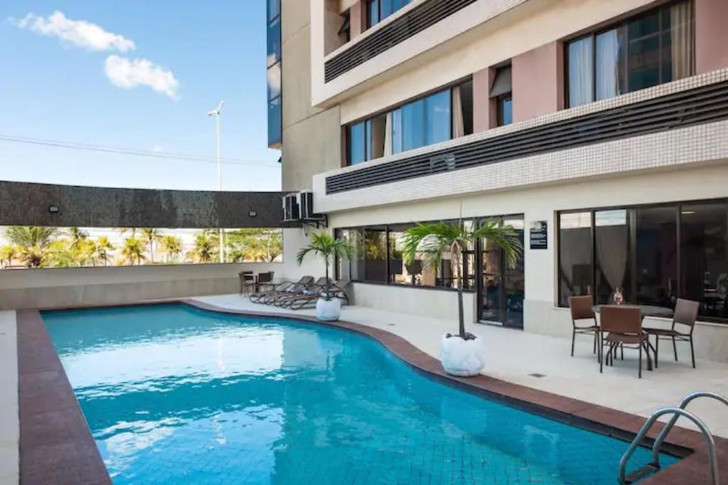 a swimming pool in front of a building at Flat no la residence com acesso a clube in Vitória