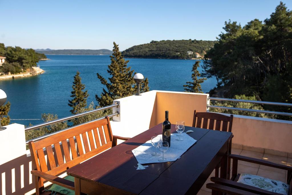 un tavolo in legno con una bottiglia di vino sul balcone di Apartment Brunac a Brbinj