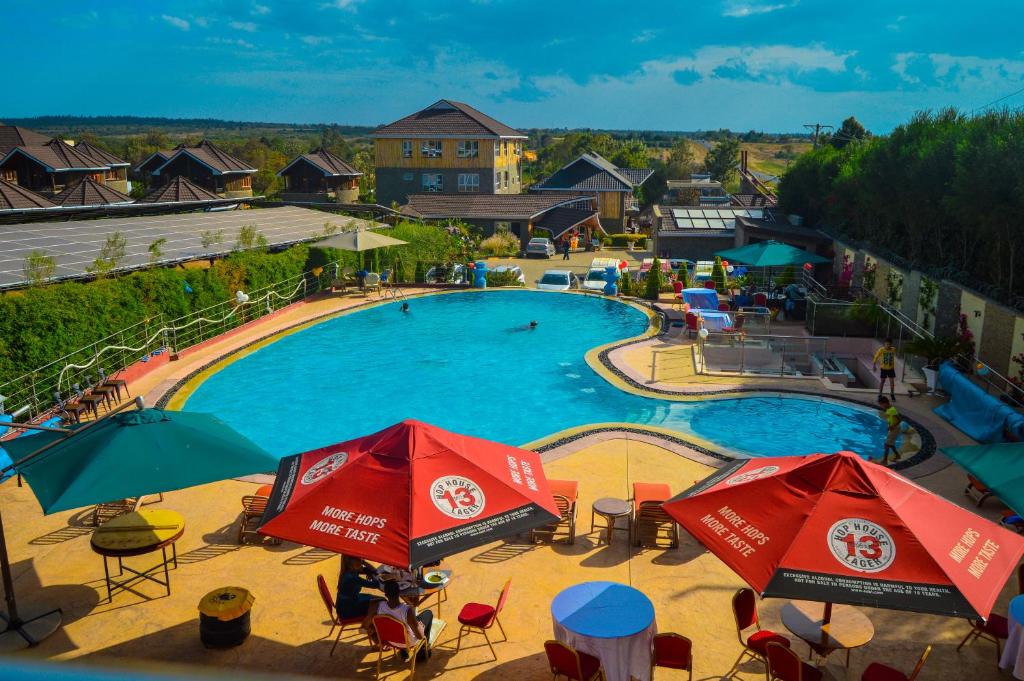 a large swimming pool with red umbrellas and chairs at Aberdare Prestige & Royal Cottages in Nanyuki