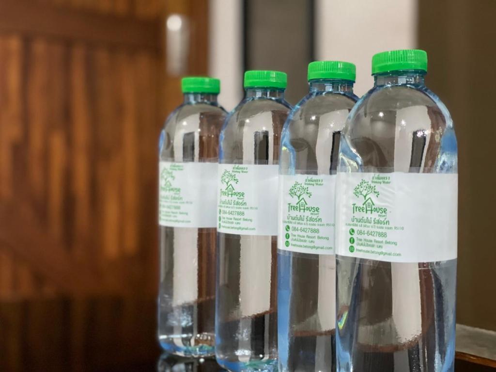 four bottles of water with green caps on a table at Tree Home ที่พักเบตงสไตล์ครอบครัว in Ban Komo Sip Paet