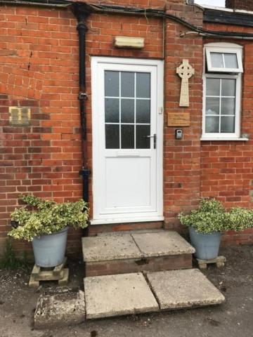 a brick house with a white door and two potted plants at The Bustard in Salisbury