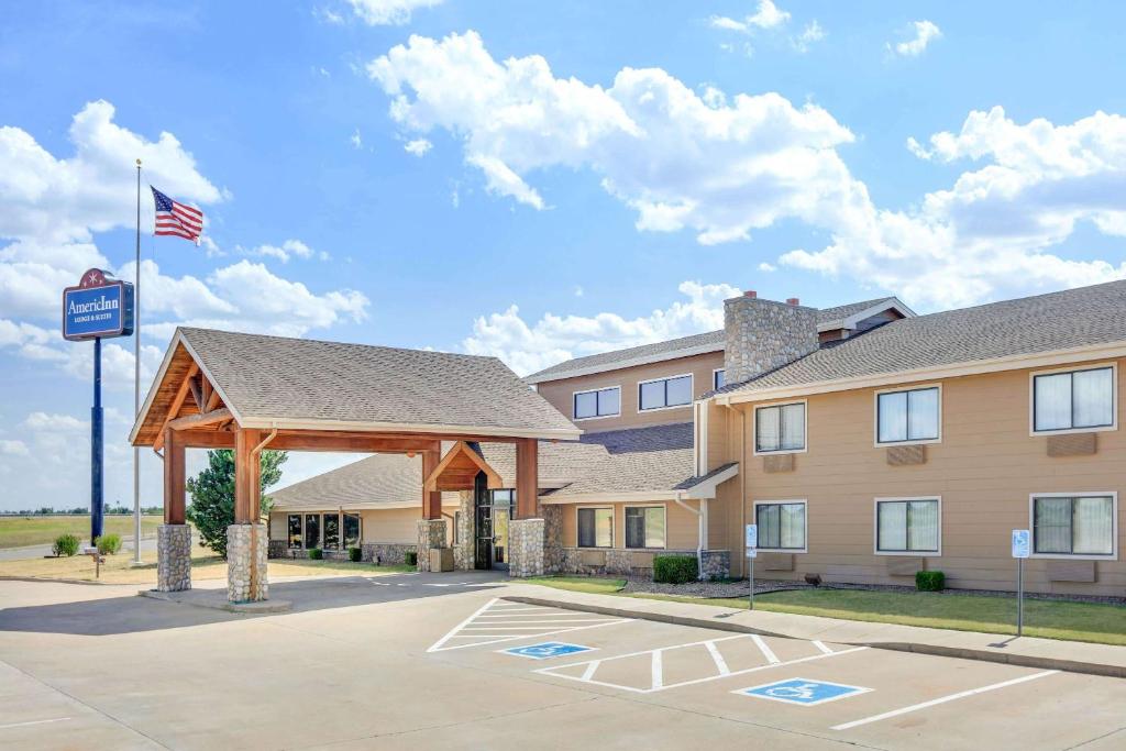 a building with an american flag in front of it at AmericInn by Wyndham Sayre in Sayre