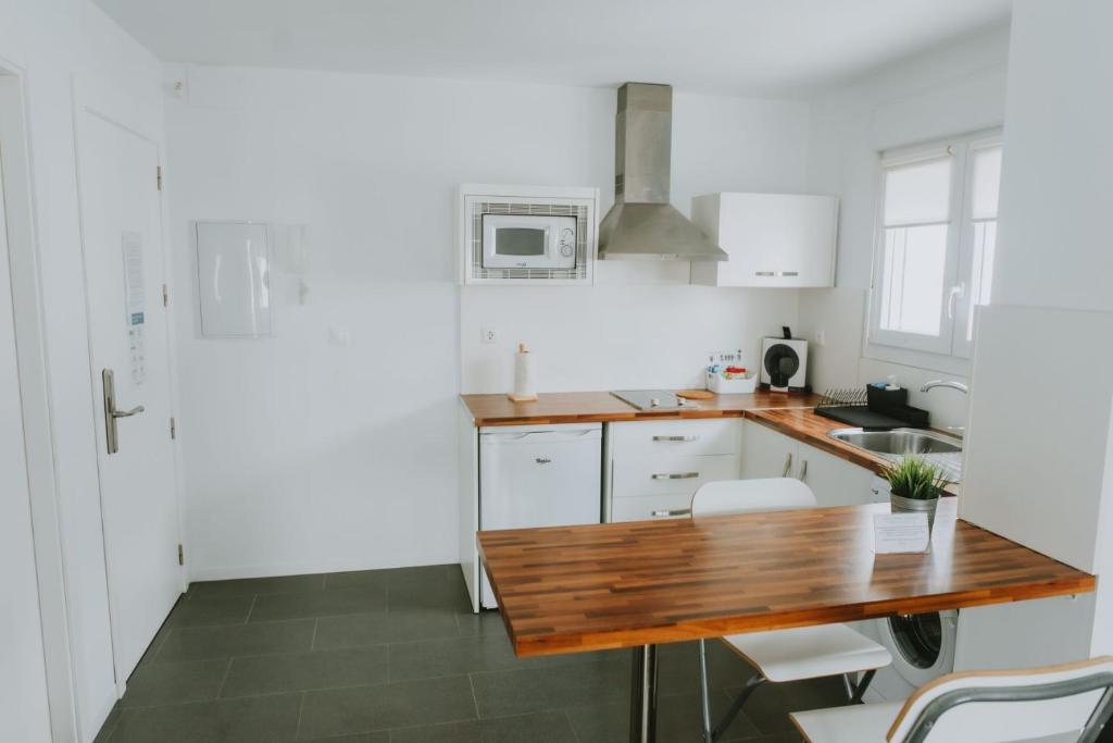 a kitchen with white cabinets and a wooden counter top at Apartamentos ZHR 2 in Zahara de los Atunes