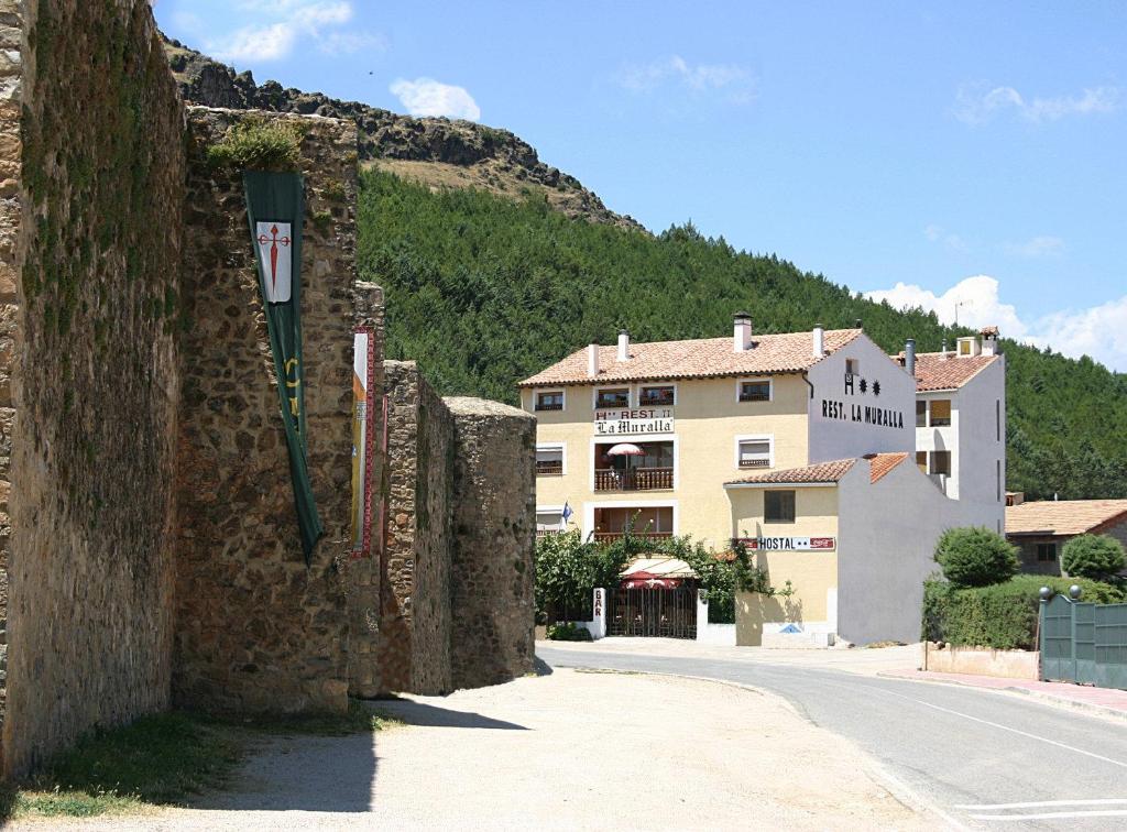 una pared de piedra junto a una calle con un edificio en Hostal Restaurante La Muralla, en Cañete