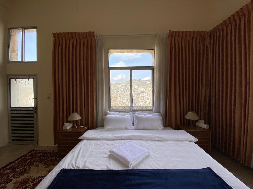 - une chambre avec un grand lit et une grande fenêtre dans l'établissement Hayat Guest House, à Naplouse