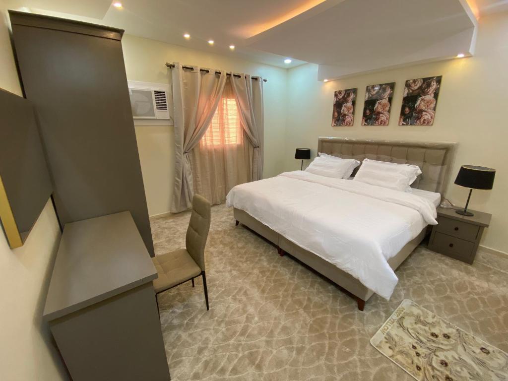 a bedroom with a large white bed and a chair at Al Diyafah Apts in Al Madinah