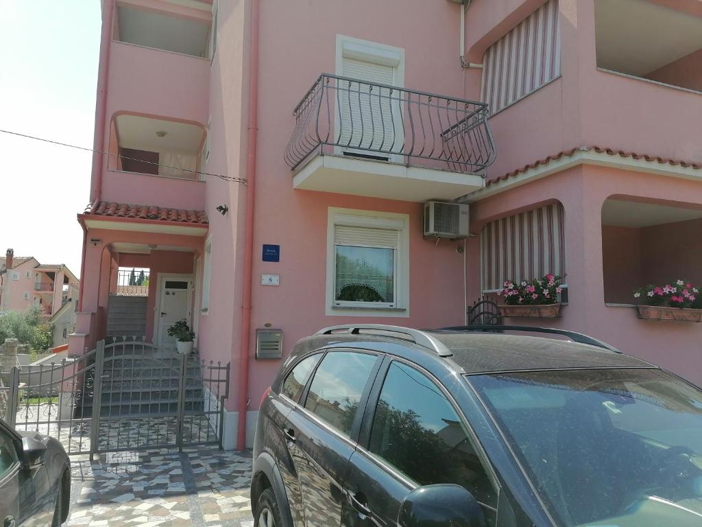 un'auto parcheggiata di fronte a un edificio rosa di Apartments Zaharija a Rovigno (Rovinj)
