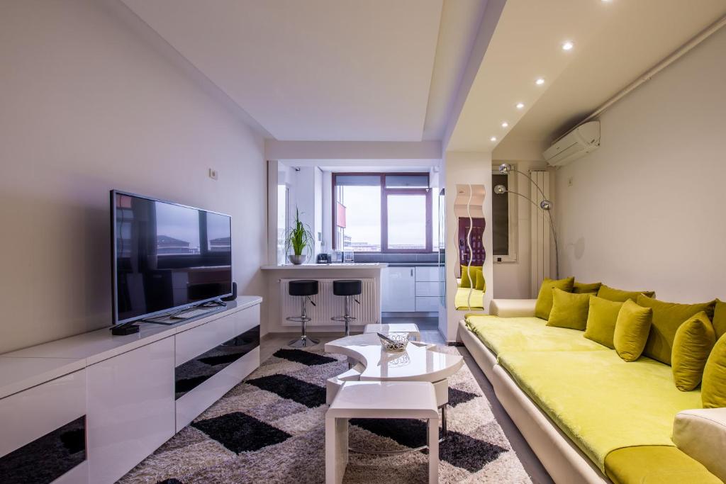 un soggiorno con divano giallo e TV di 3 Room Luxury Residence Militari M2+3 a Roşu