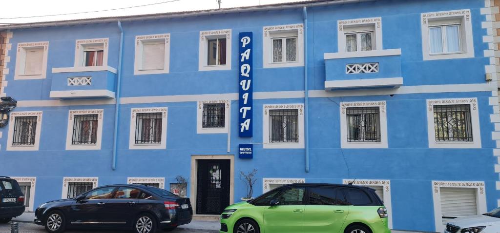 un edificio azul con dos coches estacionados frente a él en Hostal Paquita, en Madrid