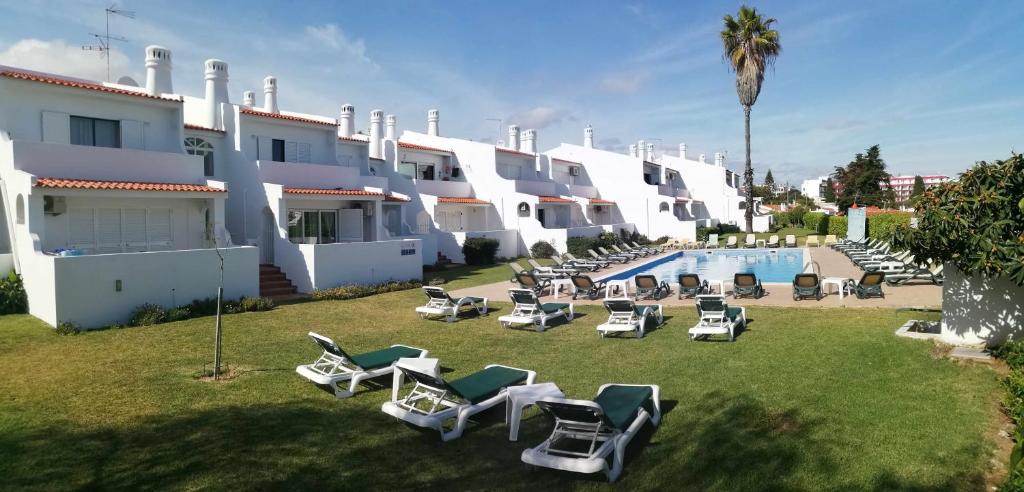 una fila di edifici bianchi con sedie a sdraio e piscina di Oura Parque Apartamentos Turisticos ad Albufeira