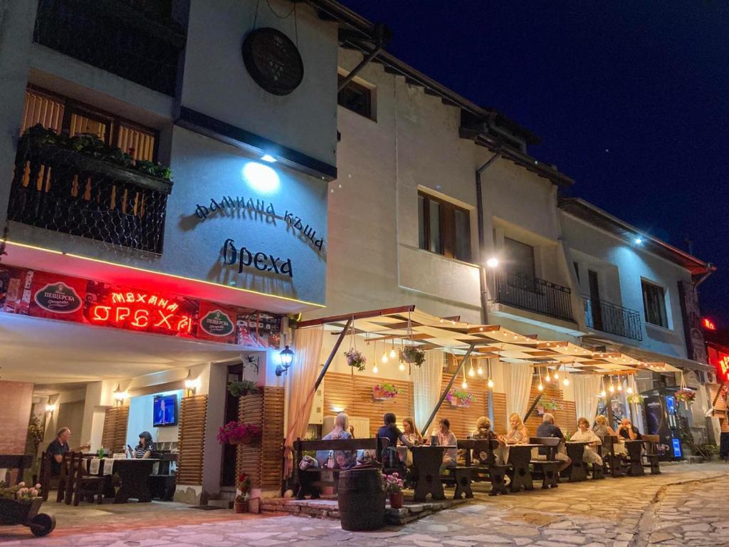 a group of people sitting outside of a restaurant at night at Family House Oreha in Bansko