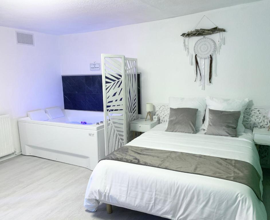 a white bedroom with a bed and a desk at Le Golf Balnéo - Cosy & SPA in Saint-Étienne