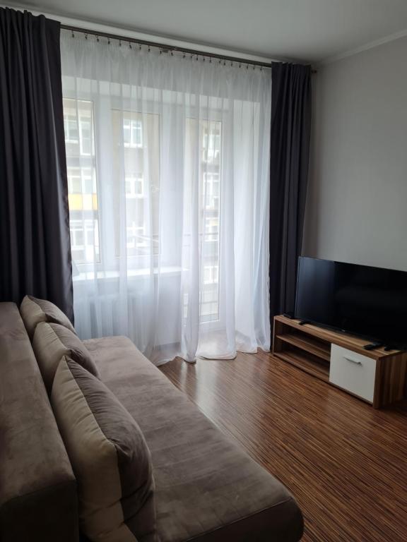 a living room with a couch and a large window at Central station in Daugavpils