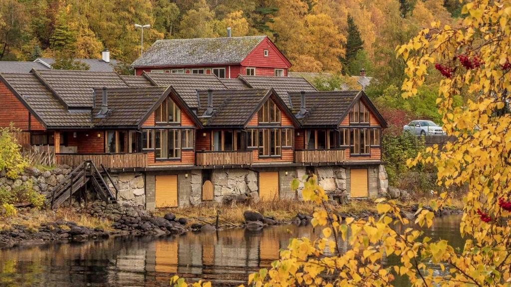 a large wooden house next to a river at Simadalsvegen 3 Hytte 1 in Eidfjord