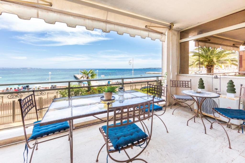 balcone con tavoli, sedie e vista sull'oceano di Apartment Seaside a Cannes