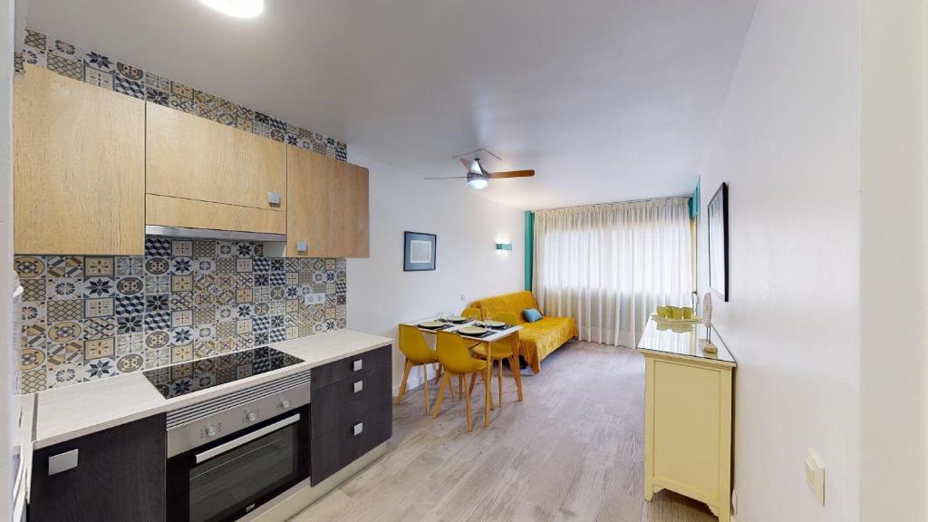 a kitchen with a table and a yellow chair at Apartamentos Eldorado in Lloret de Mar