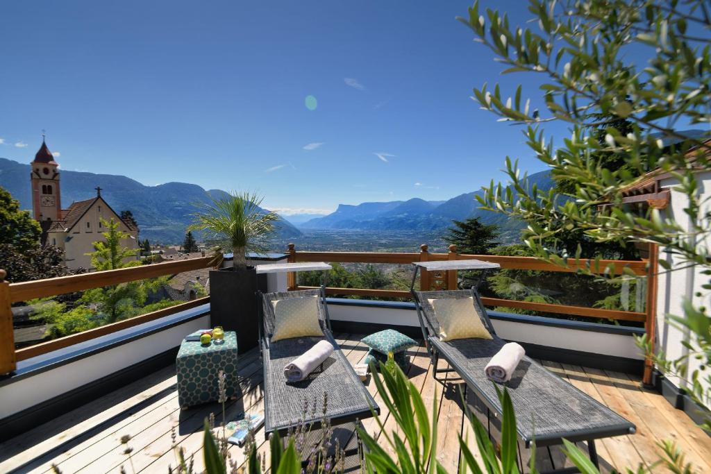 a deck with two chairs and a table on a balcony at Small Hotel Sonne in Tirolo