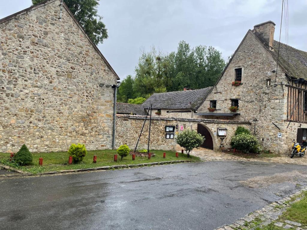 - un vieux bâtiment en pierre avec une rue en face dans l'établissement Moulin de Flagy, 