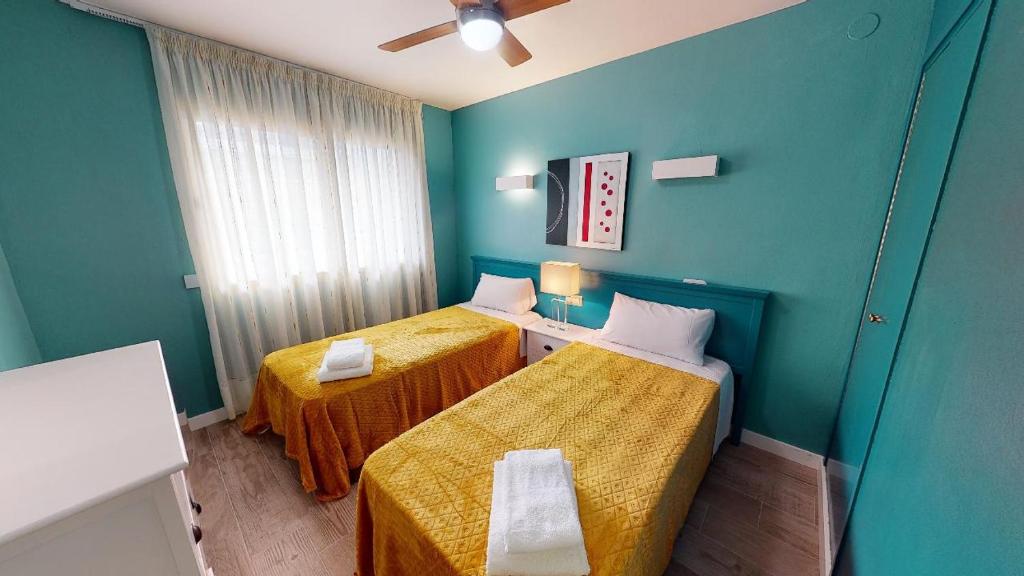 two beds in a room with blue walls at Apartamentos Eldorado in Lloret de Mar