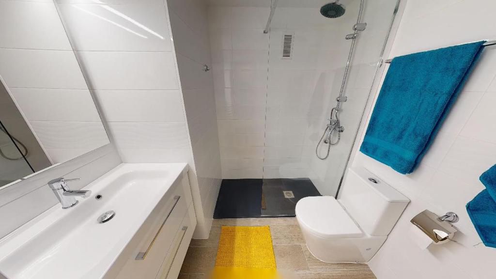 a white bathroom with a sink and a toilet at Apartamentos Eldorado in Lloret de Mar