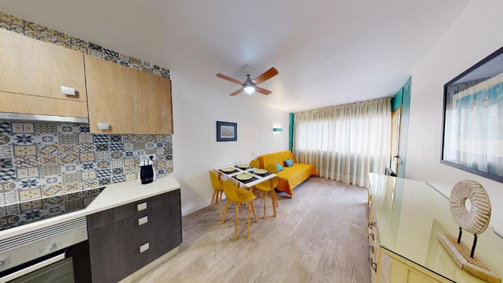 a kitchen with a table and yellow chairs in a room at Apartamentos Eldorado in Lloret de Mar