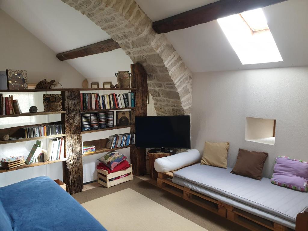 a living room with a couch and a tv at Gîte La Grange in Saint-Laurent-dʼOlt