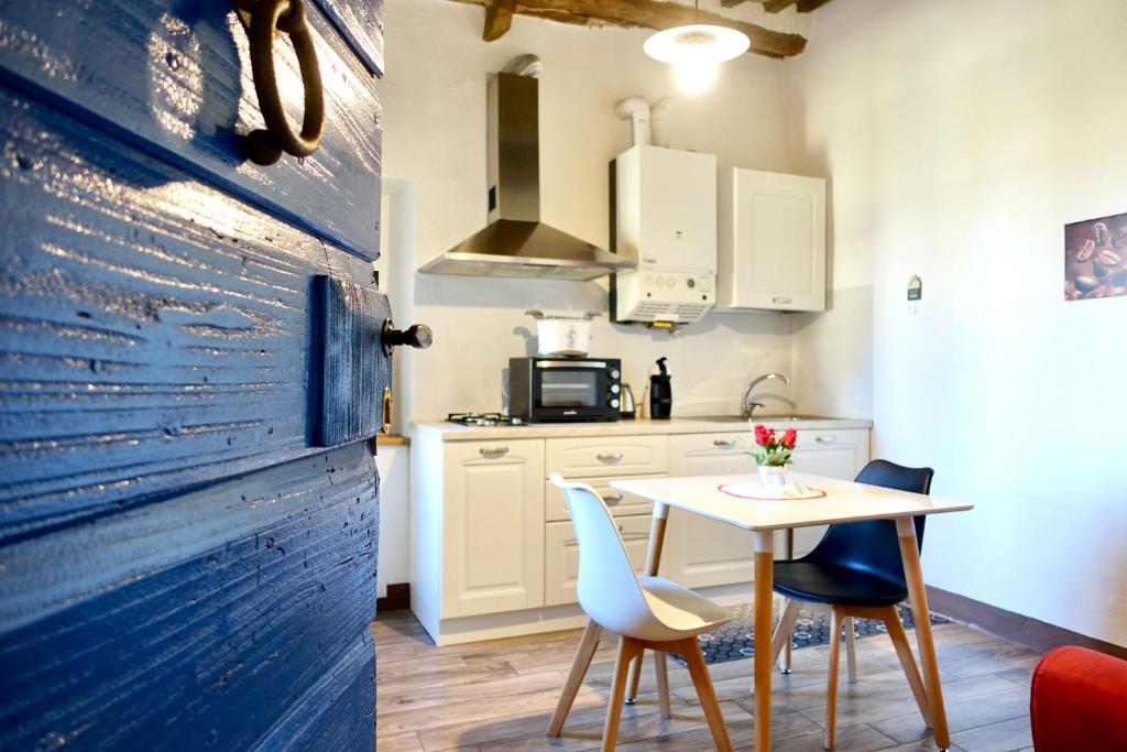 una cucina con tavolo, sedie e porta blu di Casa della Fonte - Self check-in a San Quirico dʼOrcia