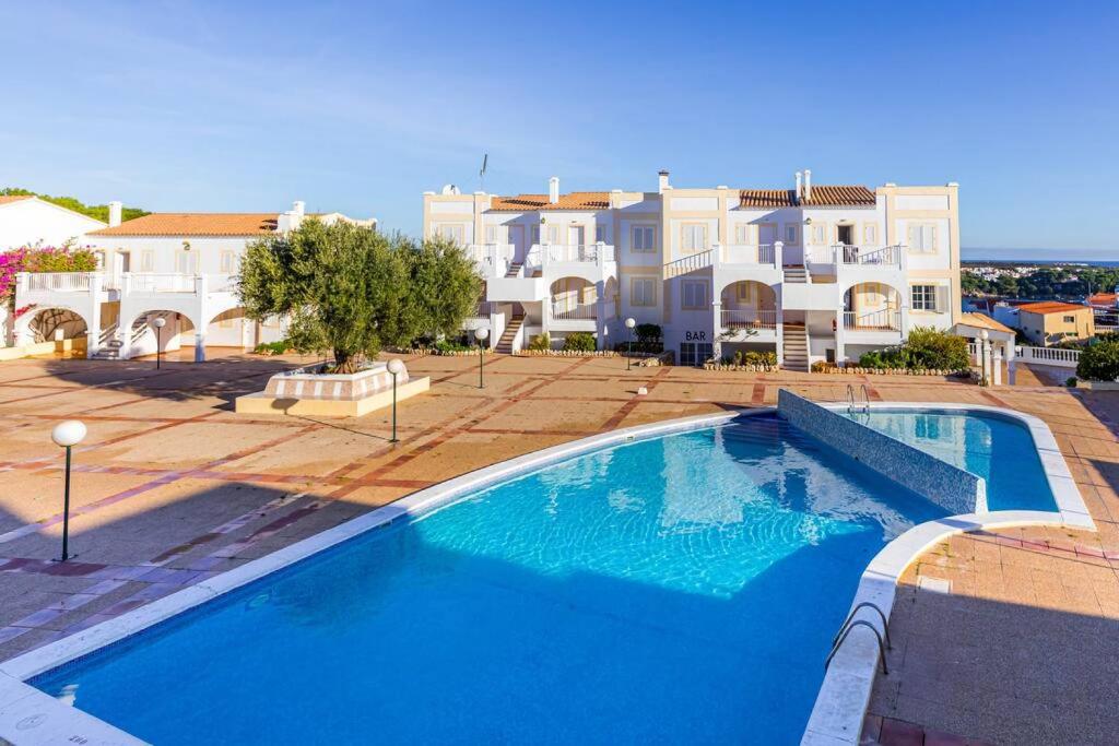 uma grande piscina em frente a uma grande casa em Apartamento CastellSol 102 em Arenal d'en Castell