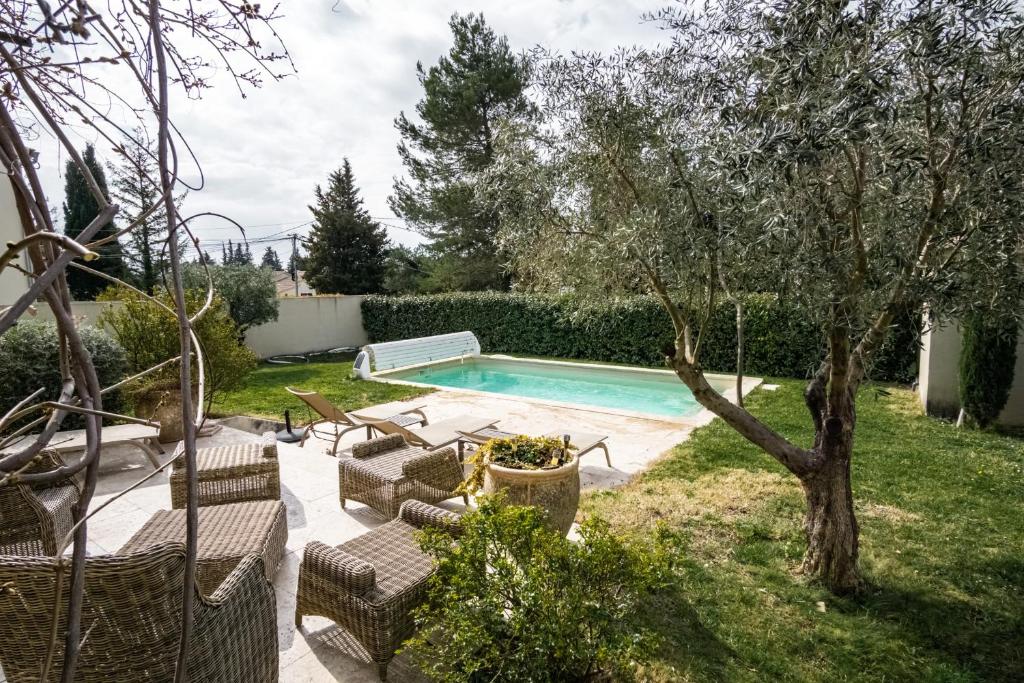 a swimming pool in a yard with chairs and a tree at La Maison de l'Yle - Villa avec piscine in L'Isle-sur-la-Sorgue