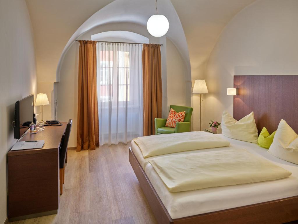 una grande camera da letto con un grande letto e una scrivania di Stadthotel Schärding a Schärding