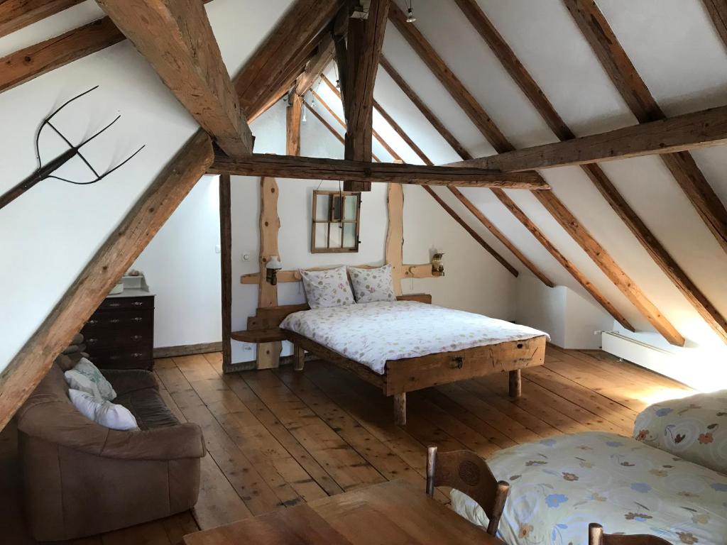 ein Schlafzimmer mit einem Bett und einem Sofa im Dachgeschoss in der Unterkunft Hôtel Von Bergen in La Sagne